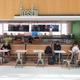 People sit down to eat at a Freshii in Toronto, Canada. Employees work in the background behind the counter.